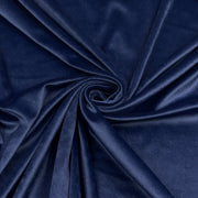 A close-up of draped navy blue velour arranged in a spiral, showing a smooth, slightly lustrous texture.