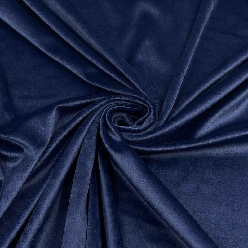 A close-up of draped navy blue velour arranged in a spiral, showing a smooth, slightly lustrous texture.