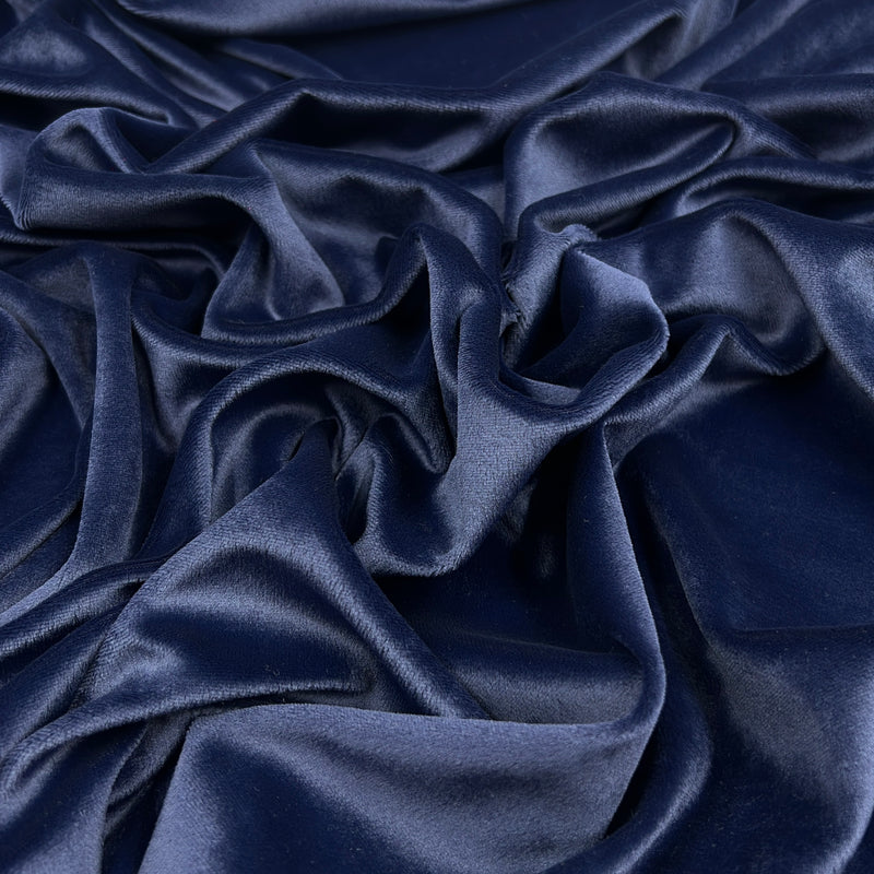 A close-up of draped navy blue velvet fabric with soft folds and a subtle sheen.