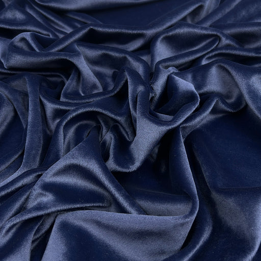 A close-up of draped navy blue velvet fabric with soft folds and a subtle sheen.
