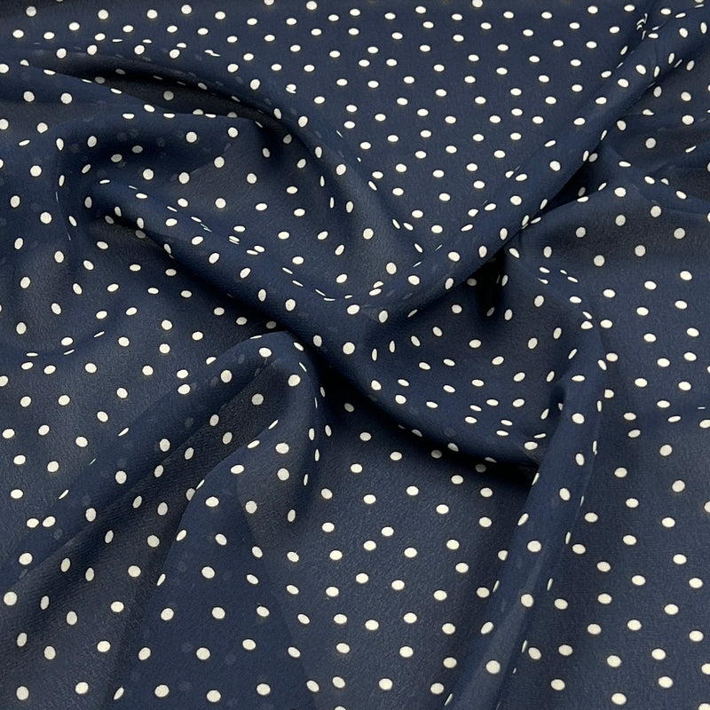 A close-up of draped navy blue fabric with a white polka dot pattern.