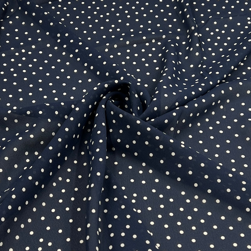 Navy blue fabric with a white polka dot pattern, shown with a central swirl to highlight the material's drape and texture.