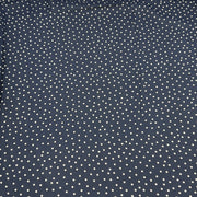 A close-up of a navy blue fabric with a repeating pattern of small white polka dots.