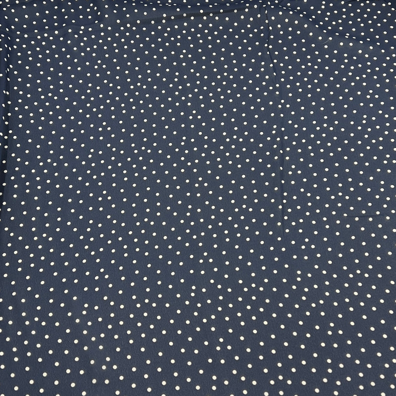 A close-up of a navy blue fabric with a repeating pattern of small white polka dots.