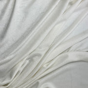 A close-up of draped off-white fabric with a soft, slightly lustrous texture and gentle folds filling the frame.