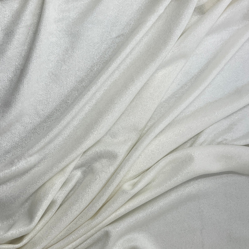 A close-up of draped off-white fabric with a soft, slightly lustrous texture and gentle folds filling the frame.