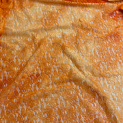 A close-up of textured orange lace fabric with a repeating floral pattern and a sheer mesh backing, showing a crinkled, slightly glossy finish.