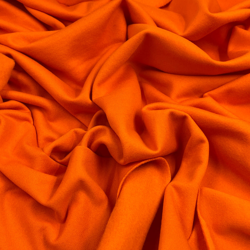 Bright orange fabric draped in soft folds, showing a smooth texture and even color.