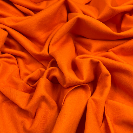 Bright orange fabric draped in soft folds, showing a smooth texture and even color.