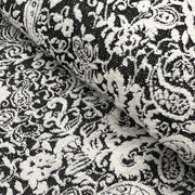 Black and white damask patterned fabric with a textured woven surface, shown in a close-up folded view.