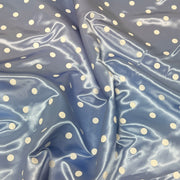Light blue satin fabric with a white polka dot pattern, shown with soft folds and a glossy sheen.