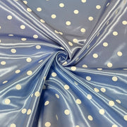Blue satin fabric with a white polka dot pattern, arranged in a central swirl to showcase its sheen and texture.