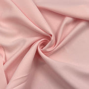 Pink textured polyester crepe fabric pulled into a swirl showing off smooth and elegant drape.