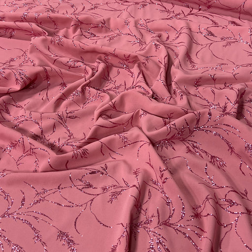 Dusty pink fabric with a delicate, repeating sequined floral vine pattern draped in soft folds.