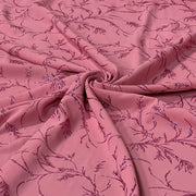 Pink fabric with a repeating floral vine pattern in a darker magenta shade and subtle sequin detailing, arranged in a central swirl.