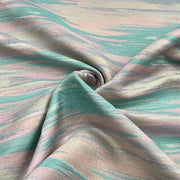 A close-up of draped fabric with an abstract brushstroke pattern in soft mint green, blush pink, and warm beige tones.