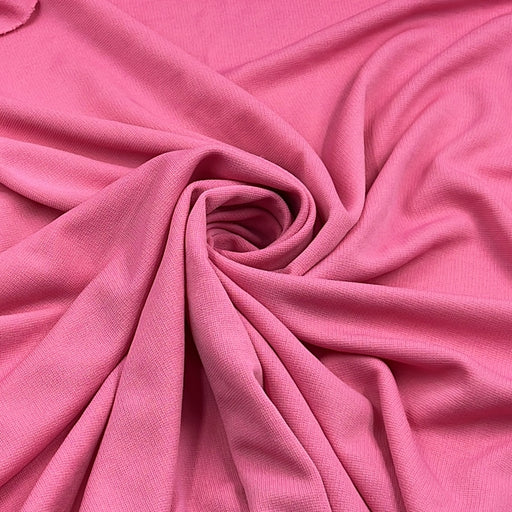 Pink ponte de roma fabric pulled into a swirl to show off structure and drape