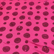 Bright pink fabric with scattered dark magenta sequined polka dots of varying sizes.