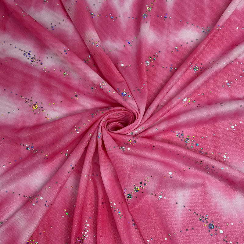 Pink and white tie-dye fabric with scattered silver, blue, and gold glitter, arranged in a spiral pattern.