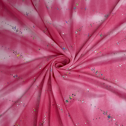 Pink and white tie-dye fabric with scattered silver, blue, and gold glitter, arranged in a spiral pattern.