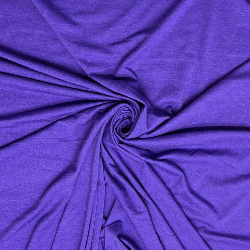 A close-up of draped purple fabric arranged in a spiral twist, showing the material's texture and color.