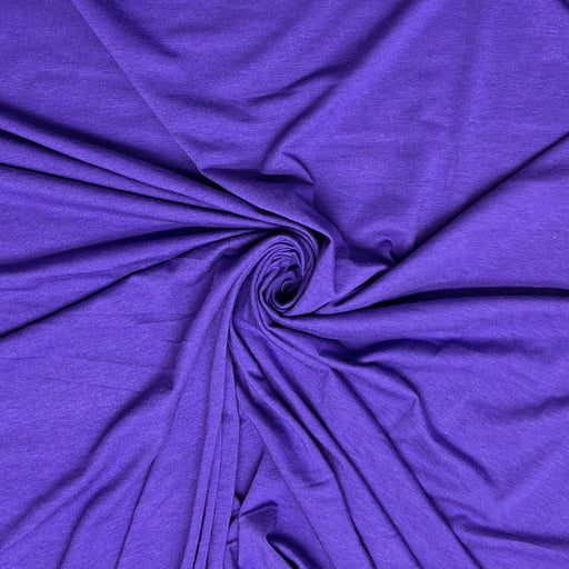 A close-up of draped purple fabric arranged in a spiral twist, showing the material's texture and color.