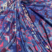 A close-up of draped fabric with an intricate paisley and floral pattern in shades of blue, burgundy red, and cream.