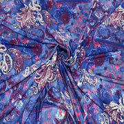 A close-up of a draped fabric with a blue paisley pattern featuring pink, burgundy, and white details.