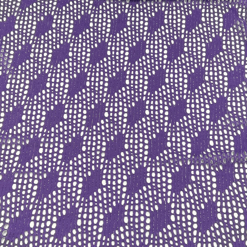Purple and white patterned lace fabric with a repeating openwork floral and geometric design.
