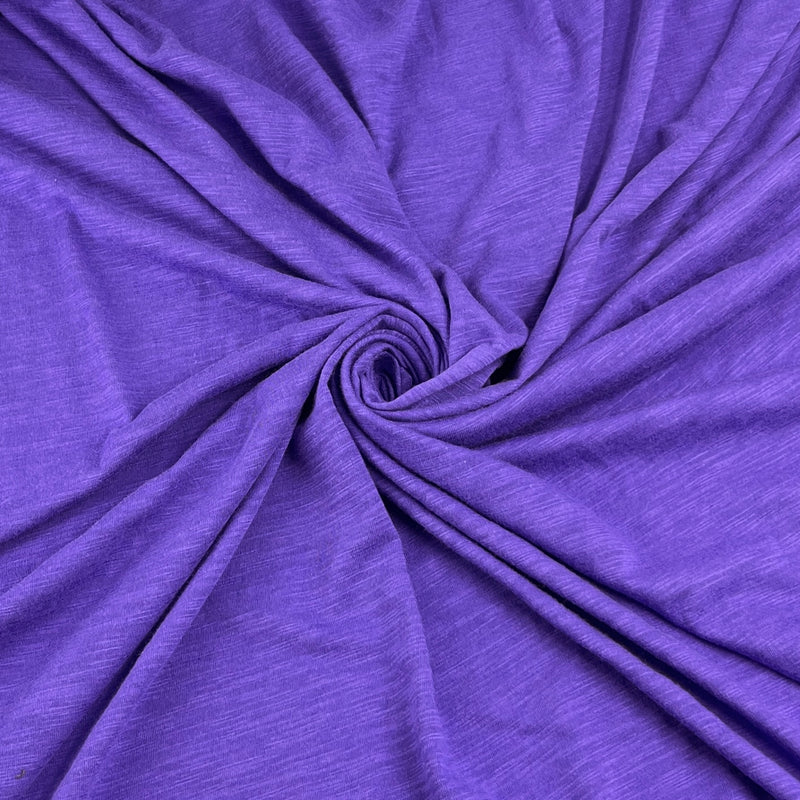 Purple heathered fabric draped in a spiral pattern, showing its soft texture and drape.