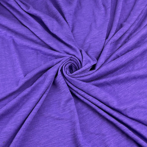 Purple heathered fabric draped in a spiral pattern, showing its soft texture and drape.