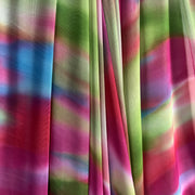 A close-up of draped sheer fabric with a multicolor abstract print featuring pink, green, blue, and yellow tones.
