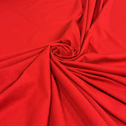 Bright red fabric draped in a spiral pattern, showing its smooth texture and soft folds.