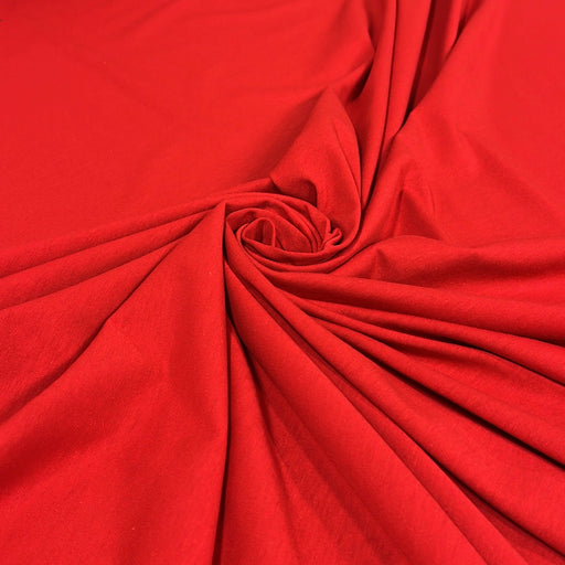Bright red fabric draped in a spiral pattern, showing its smooth texture and soft folds.