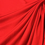 A close-up of bright red fabric draped in soft folds, showing the material texture and color.