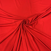 A close-up of bright red fabric arranged in a spiral drape, showing the material's texture and color.