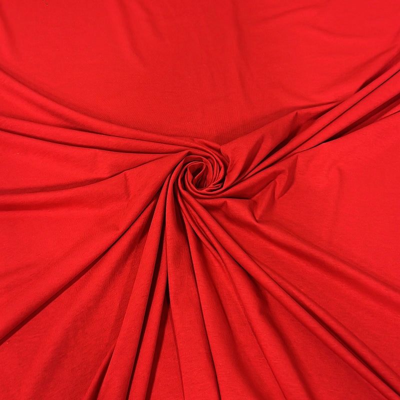 A close-up of bright red fabric arranged in a spiral drape, showing the material's texture and color.