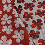 Two close-up views of a patterned fabric. One side shows a deep red background with large white floral motifs, and the other shows a light gray striped background with smaller red floral motifs.