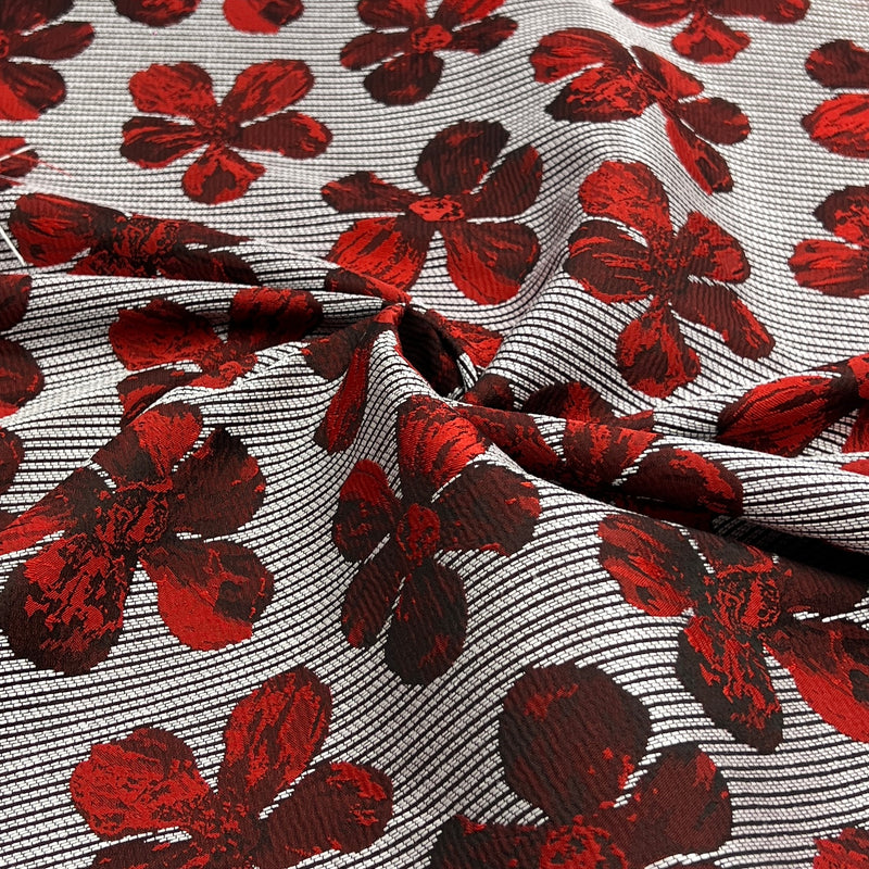 A close-up of patterned fabric with large dark red floral motifs over a gray and white striped background.