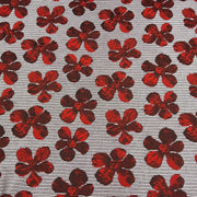 A close-up of a woven fabric featuring a repeating pattern of red and dark red floral motifs on a gray and white striped background.