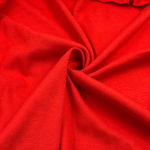 A close-up of bright red fabric arranged in a spiral drape, showing the material texture and color.