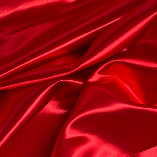Red satin fabric with a glossy, lustrous sheen, draped in soft folds and creases.
