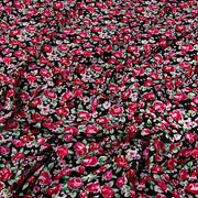 Black fabric with an all-over dense floral print featuring red, pink, and white flowers with green leaves.