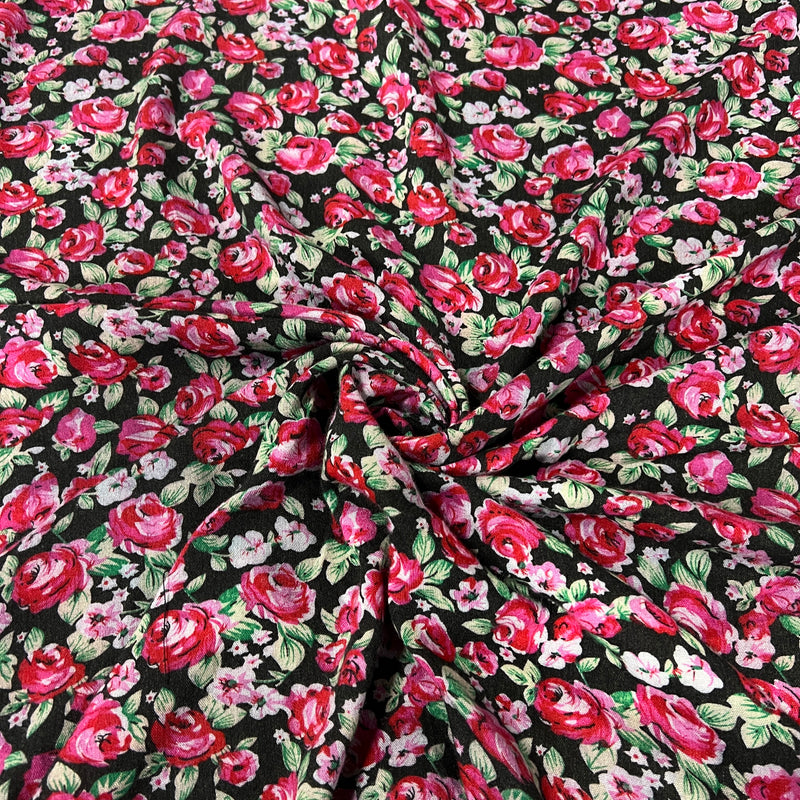 Black fabric with a dense red and pink floral print, featuring green leaves and light pink blossoms, styled with a central swirl.