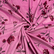 Pink fabric with a dark red and black floral vine pattern, arranged in a spiral drape to show texture and print detail.