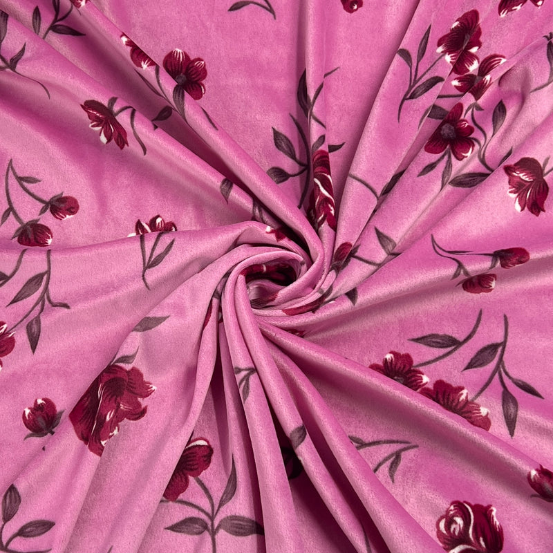 Pink fabric with a dark red and black floral vine pattern, arranged in a spiral drape to show texture and print detail.
