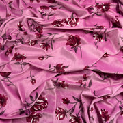 Pink velour fabric with a dark red and burgundy floral print, draped to show its sheen and texture.