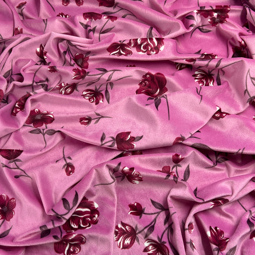 Pink velour fabric with a dark red and burgundy floral print, draped to show its sheen and texture.
