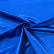 A close-up of bright royal blue satin fabric draped in elegant folds, gathered into a spiral twist in the center.