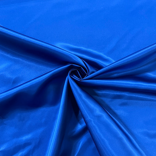 A close-up of bright royal blue satin fabric draped in elegant folds, gathered into a spiral twist in the center.